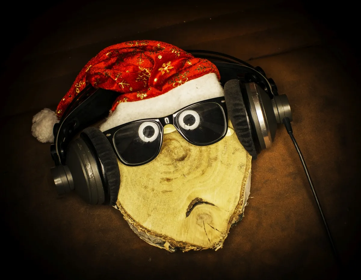 Wood slice arranged like a face with sunglasses, headphones, and a Santa hat
